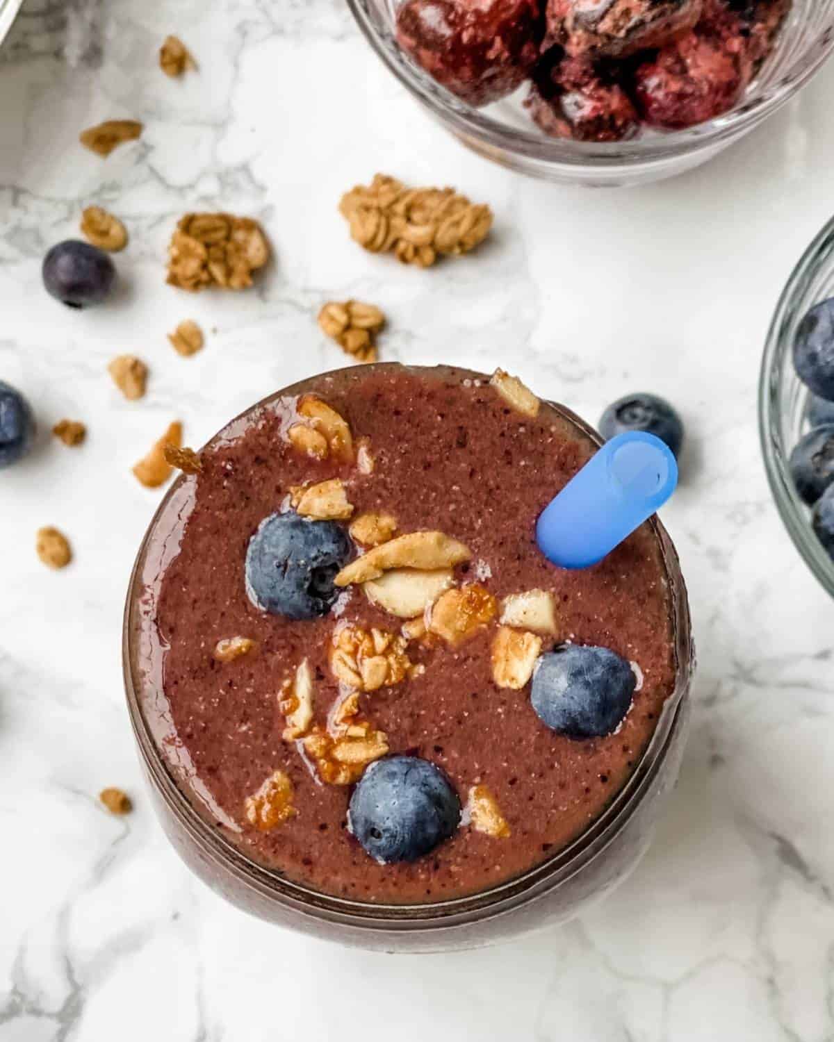 cherry blueberry smoothie with extra blueberries and a sprinkle of granola on top.