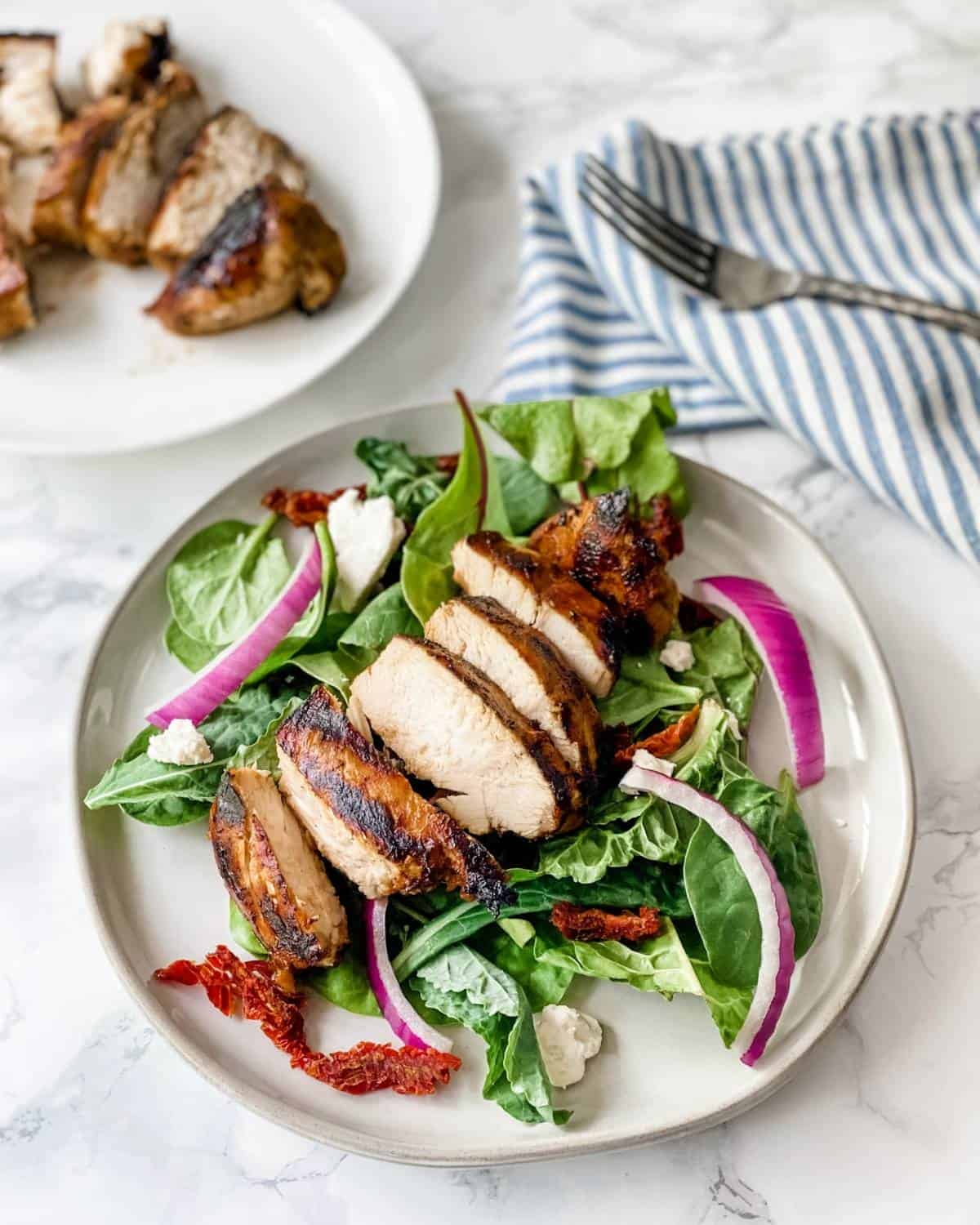 slices of grilled balsamic chicken onto of salad