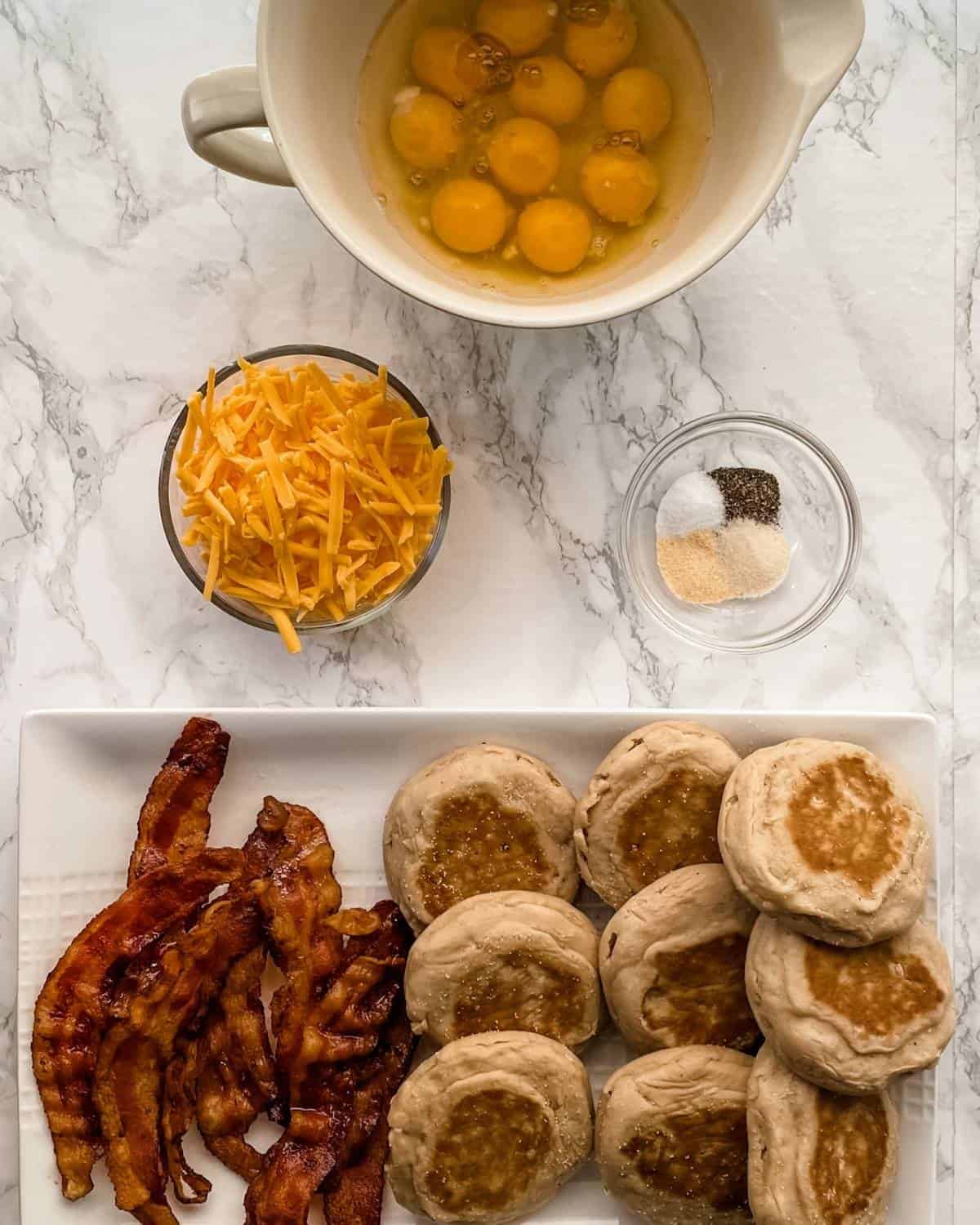 The ingredients (eggs, spices, bacon, and English muffins) to make a batch of breakfast sandwiches for the freezer.