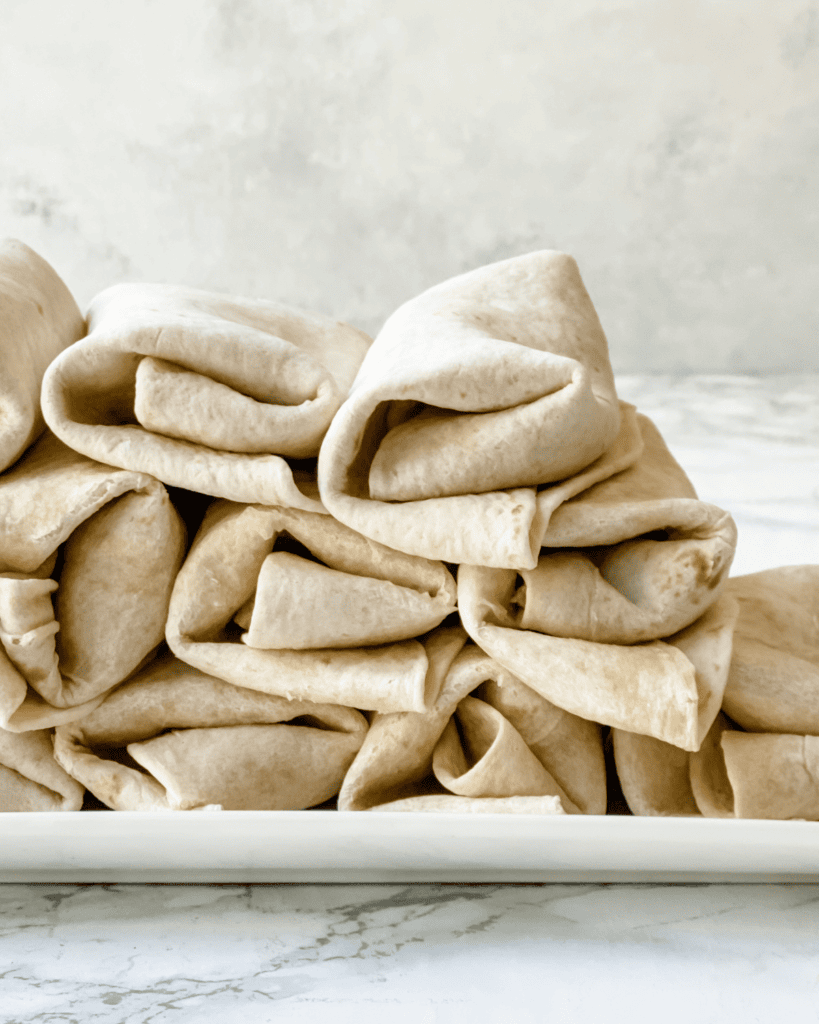 stack of breakfast burritos on a platter.