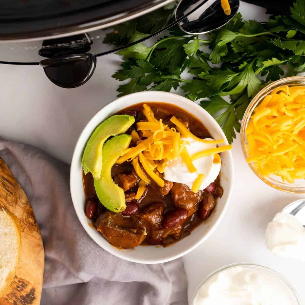 a bowl of chunky chili with avocado and cheese.