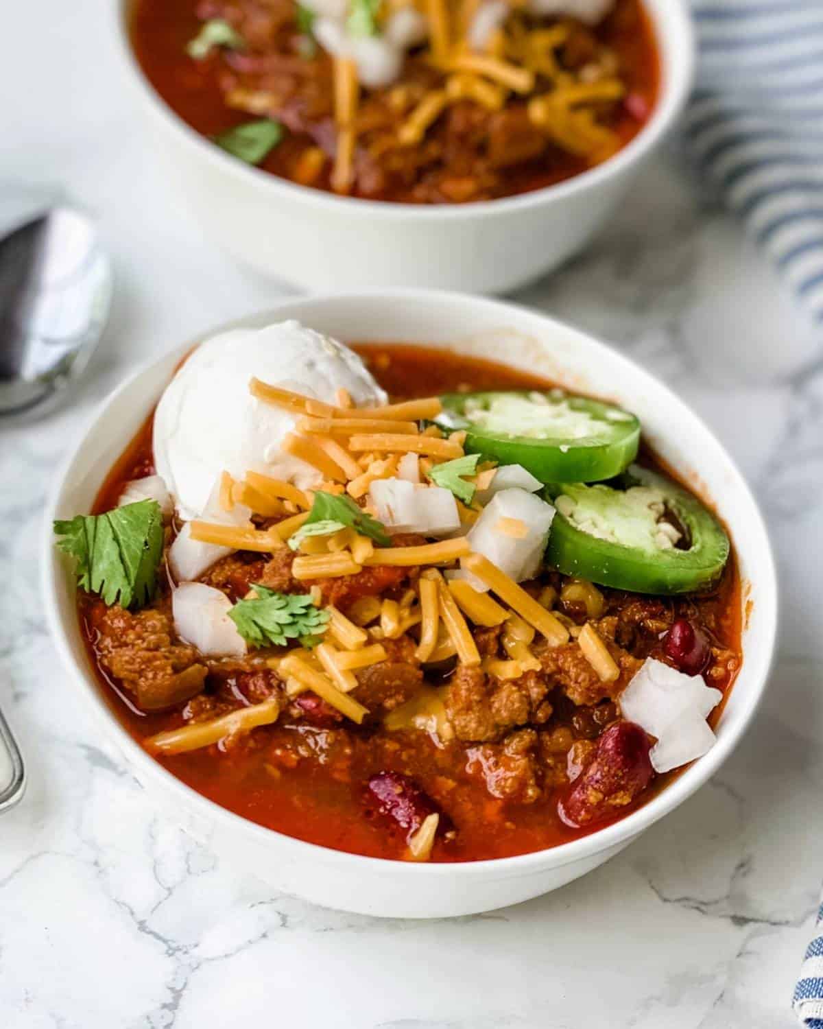 turkey chili made in the crockpot. In a bowl with cheese and onions on top.