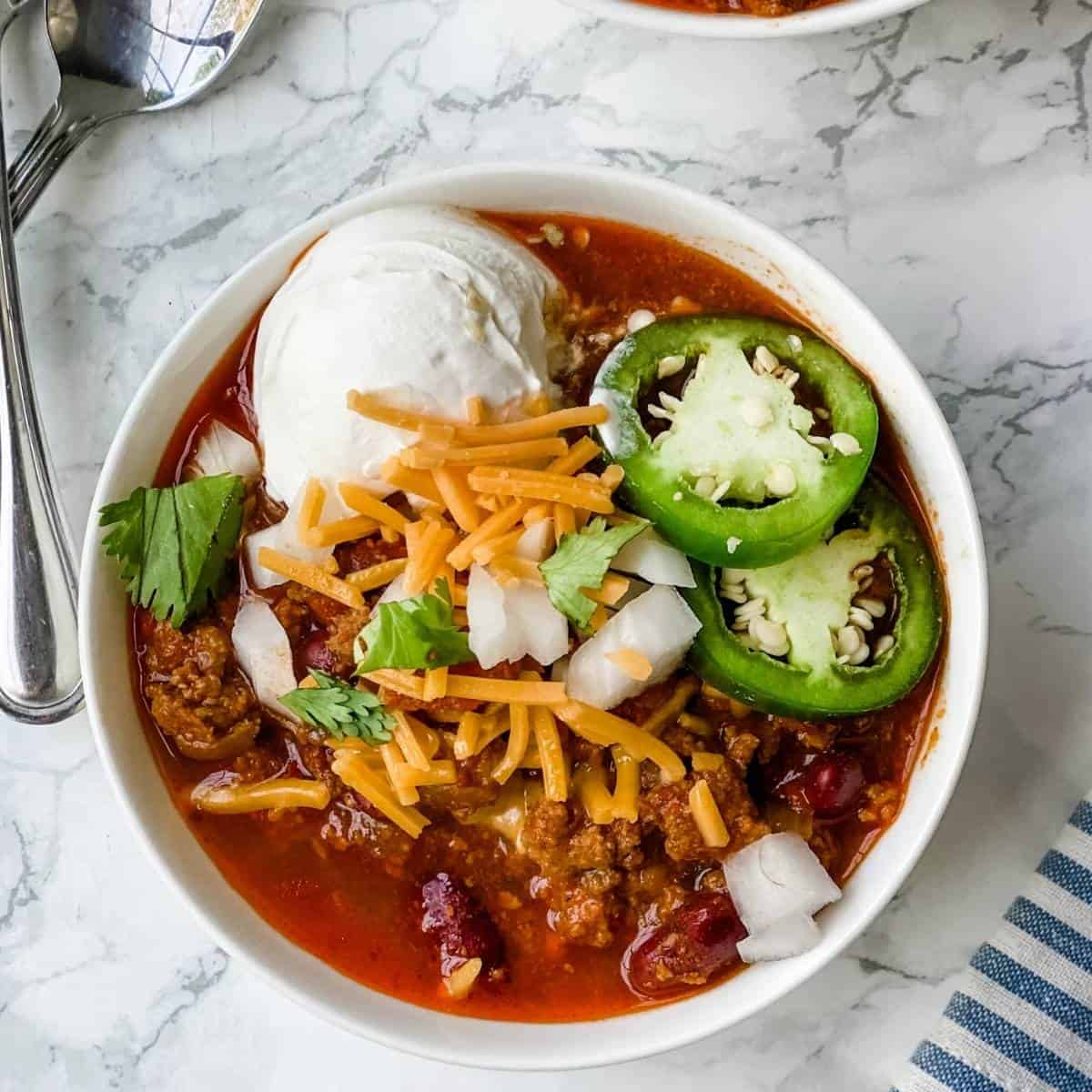 a delicious bowl of ground turkey chili with sliced jalapeños and cheese.