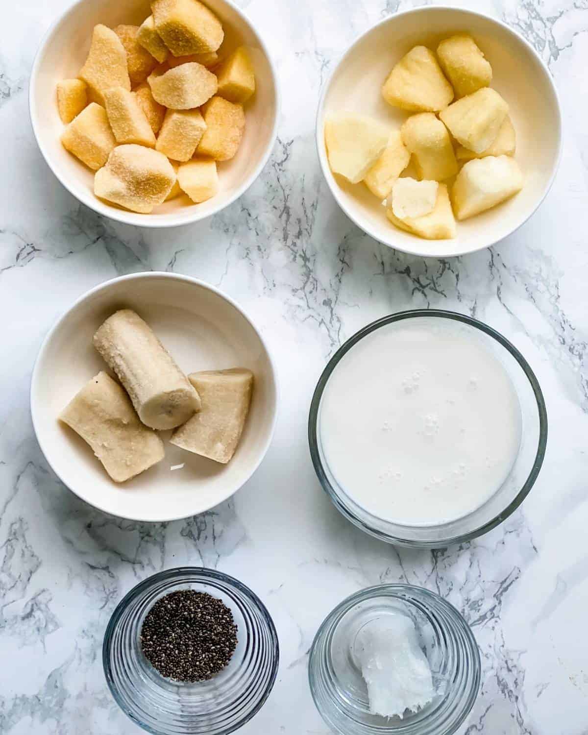 tropical smoothie ingredients. Pineapple, mango, banana, coconut milk, coconut oil, and chia seeds.