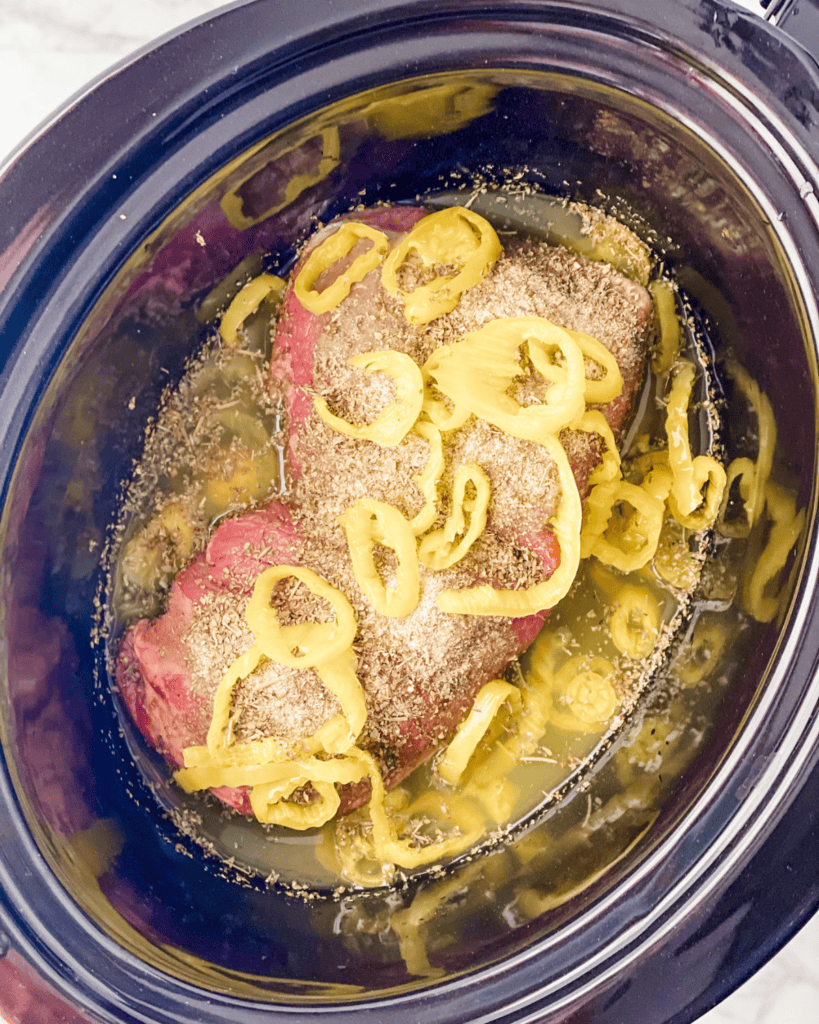 beef with seasoning and peppers in crockpot.