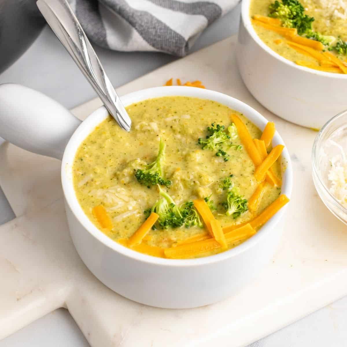 healthy broccoli cheddar soup in a white bowl on cutting board