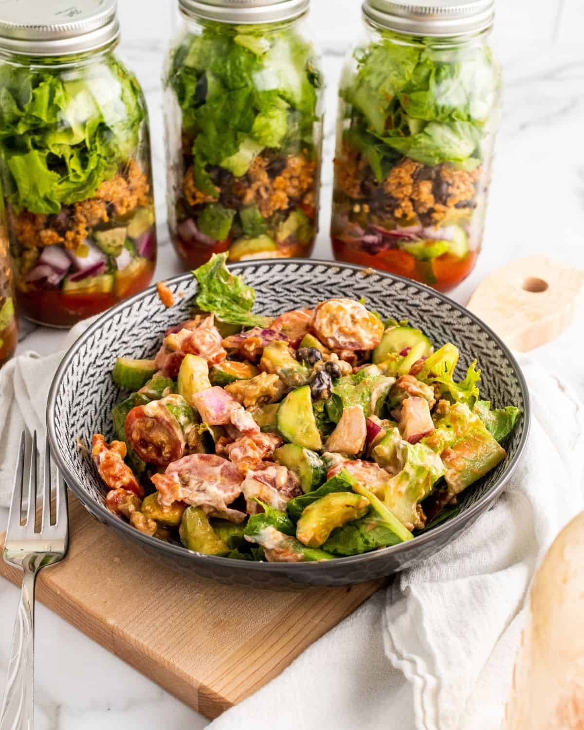 taco salad in a bowl in front of jars of salad.