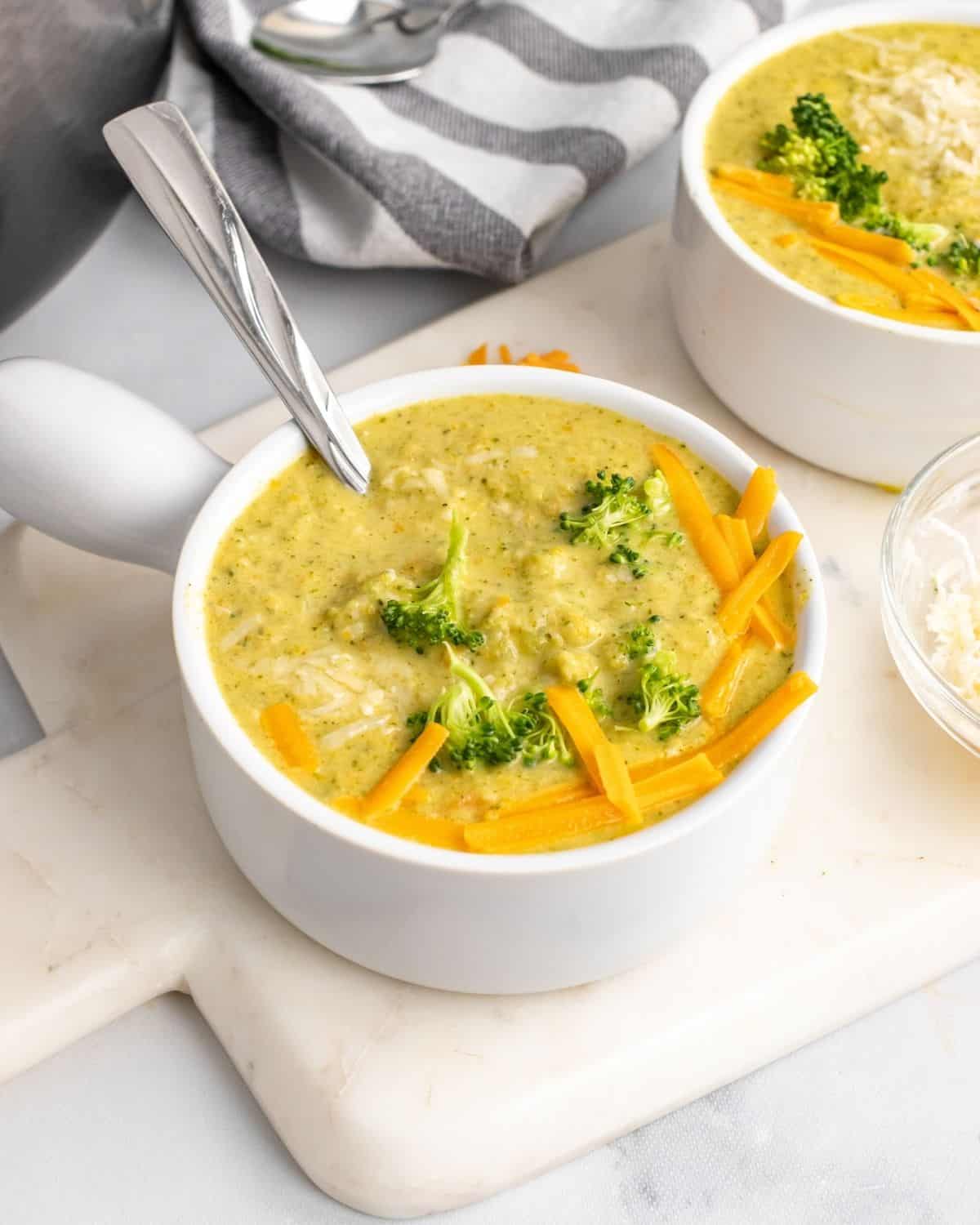 broccoli cheese soup in a white bowl with cheddar.
