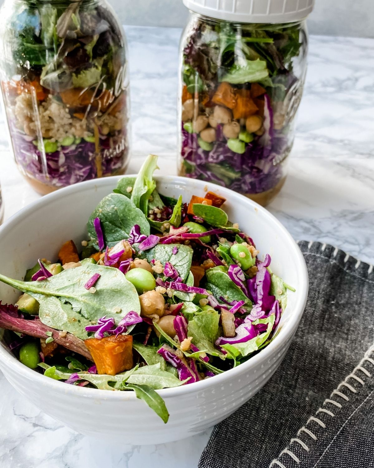 a bowl filled with spicy Thai salad with mason jar salads behind it.