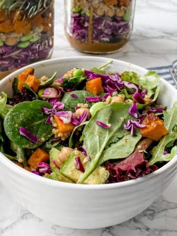 Spicy Thai Salad in a Jar. In a bowl with layered salads in the back