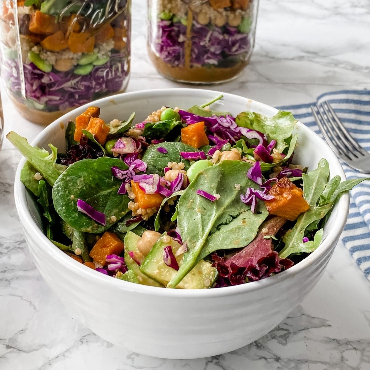 Spicy thai salad in a jar in a bowls with jars behind it.