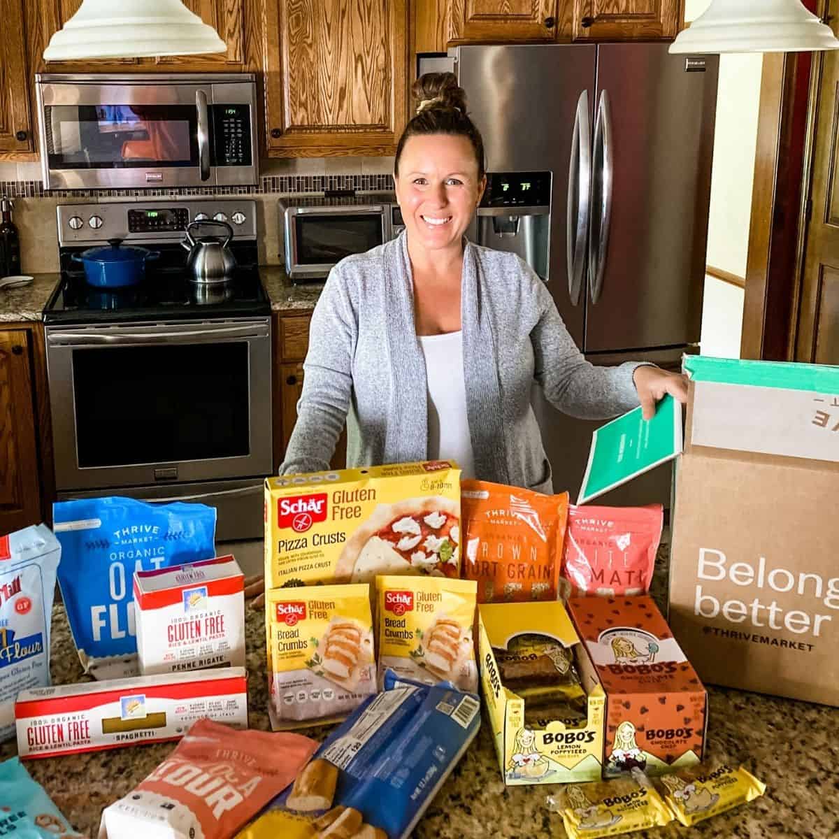 Tammy Overhoff with a box from thrive market filled with all gluten free food items.