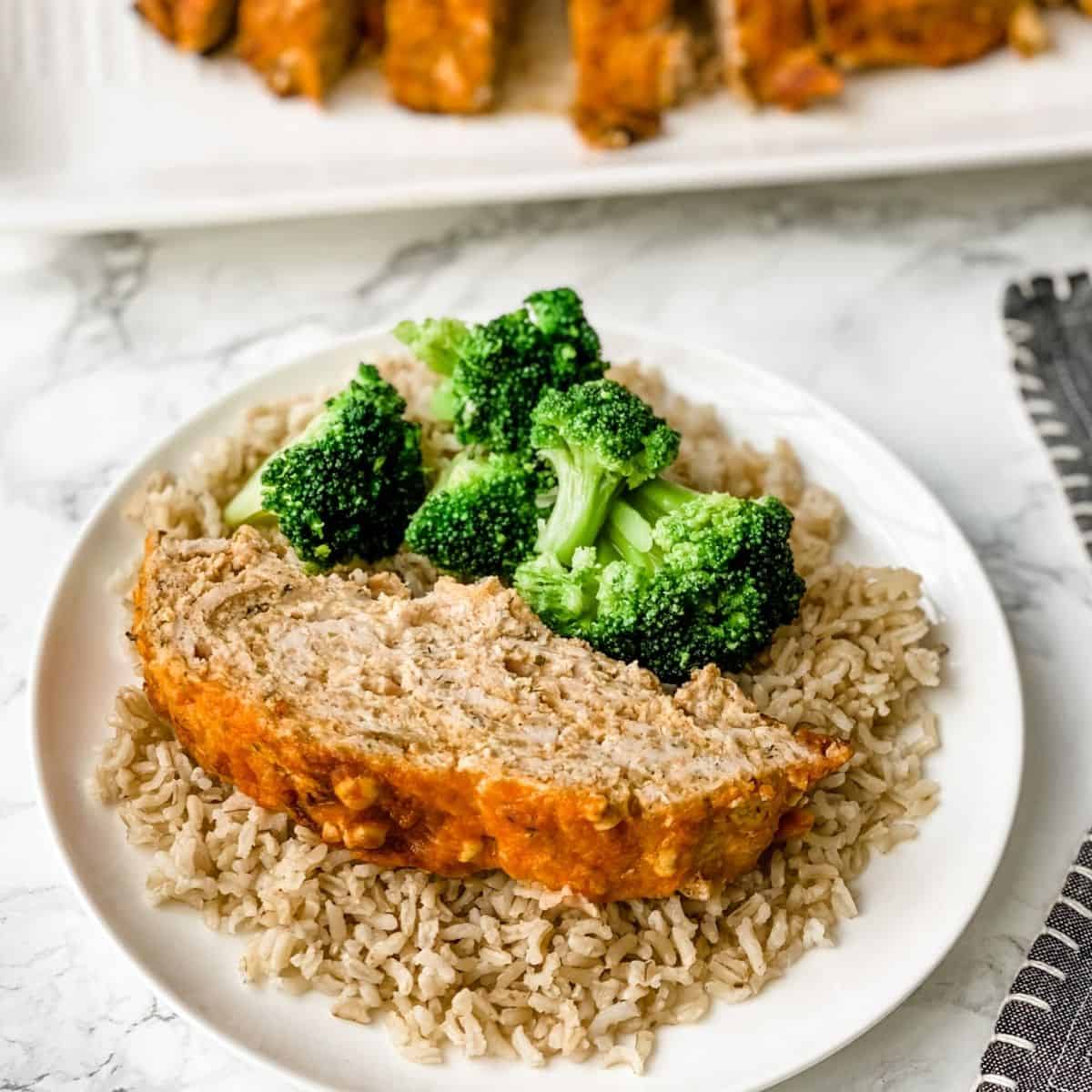 buffalo chicken meatloaf on a plate with rice and broccoli.