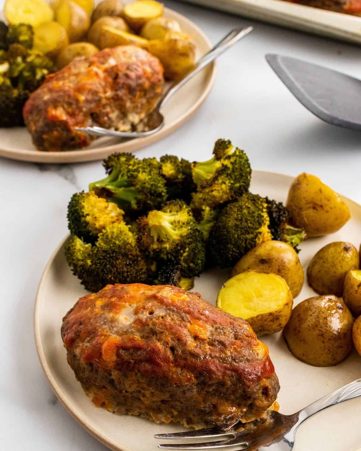 two plates with a piece of meatloaf, potatoes, and broccoli