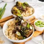 slow cooker beef and broccoli healthy recipe. Two bowls of beef broccoli on a cutting board.