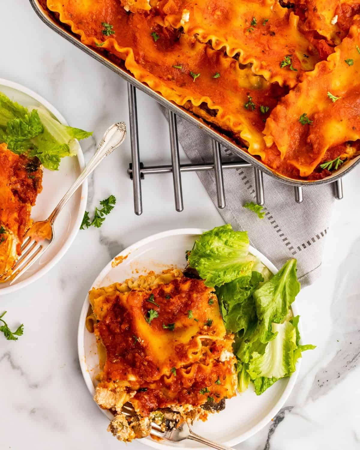 overhead picture of lasagna on plate with a pan of lasagna next to it.
