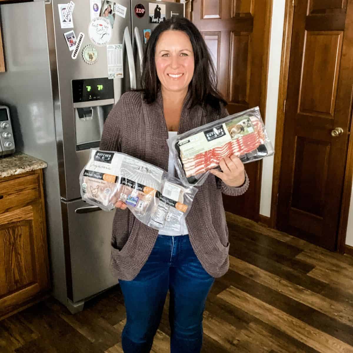 Tammy Overhoff holding a package of Butcherbox chicken things and Butcher Box box for her Butcher Box Review