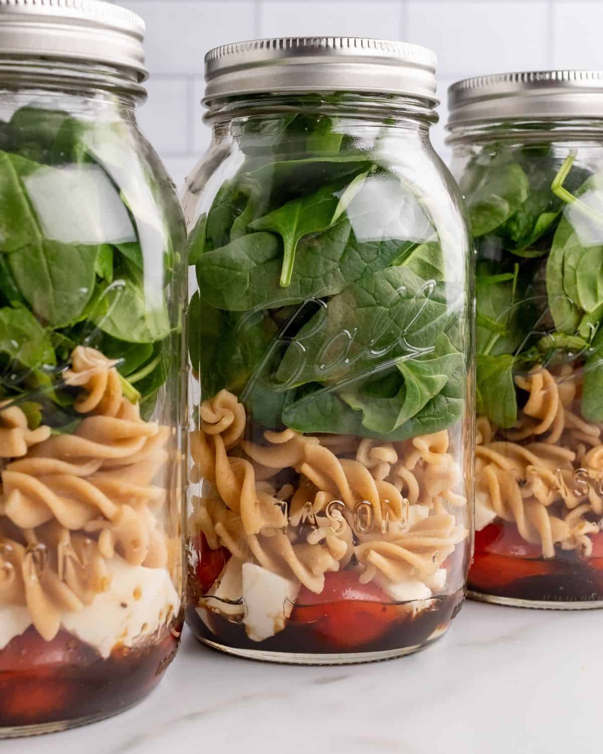 spinach salad with pasta layered in a jar.