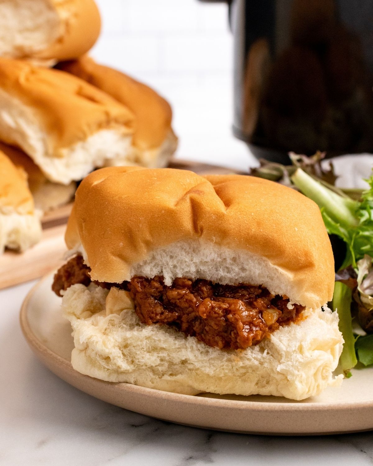 closeup picture crockpot sloppy joes on a hamburger bun.