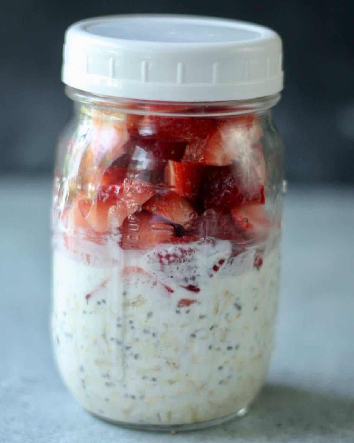 strawberry cheesecake overnight oats ingredients layered in a mason jar.