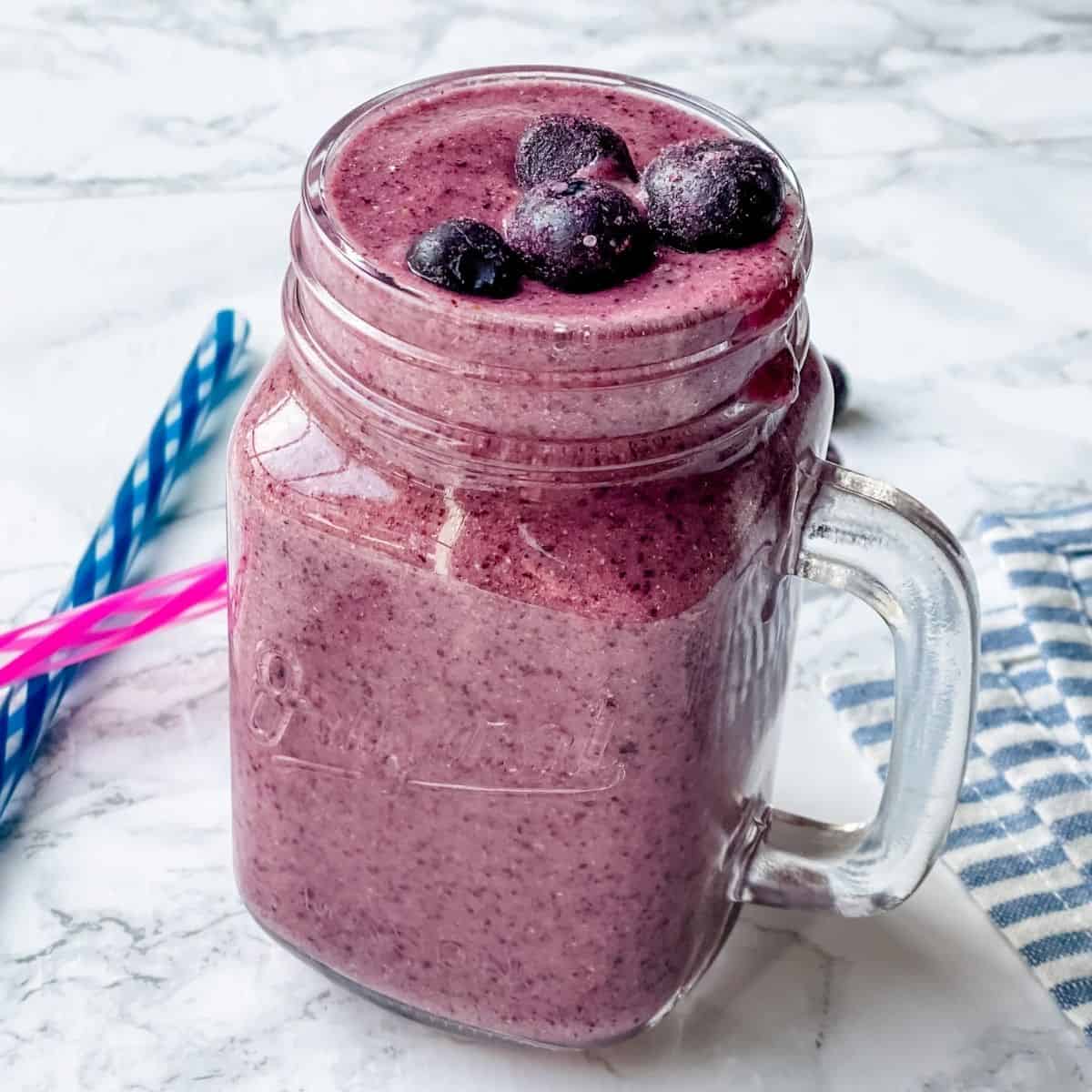 blueberry smoothie recipe in a mason jar with straws on the side