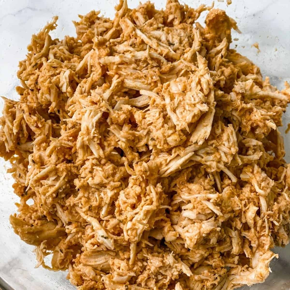 crockpot buffalo chicken shredded in a glass bowl.