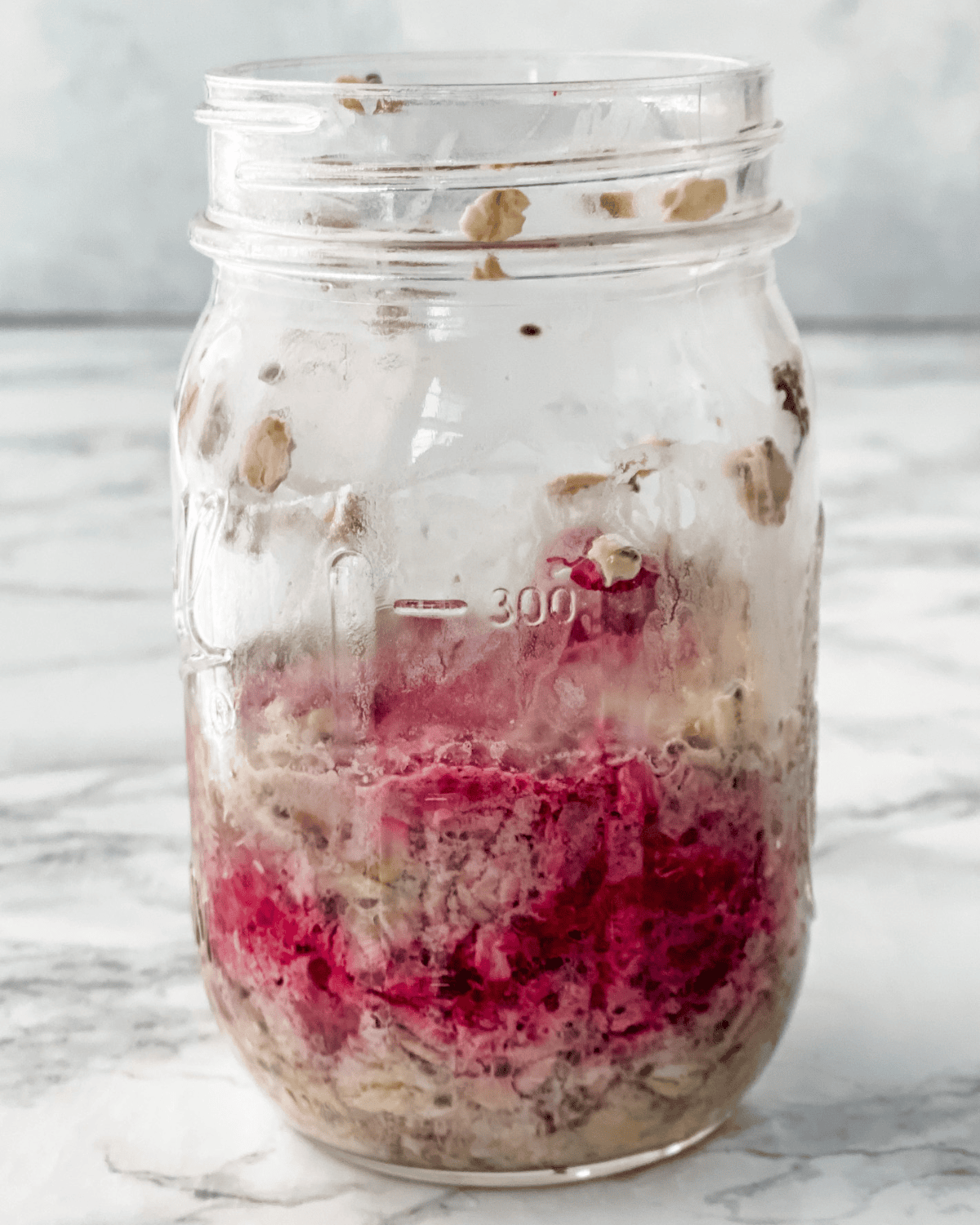 milk, oats, chia seeds, and raspberries mixed in a jar.