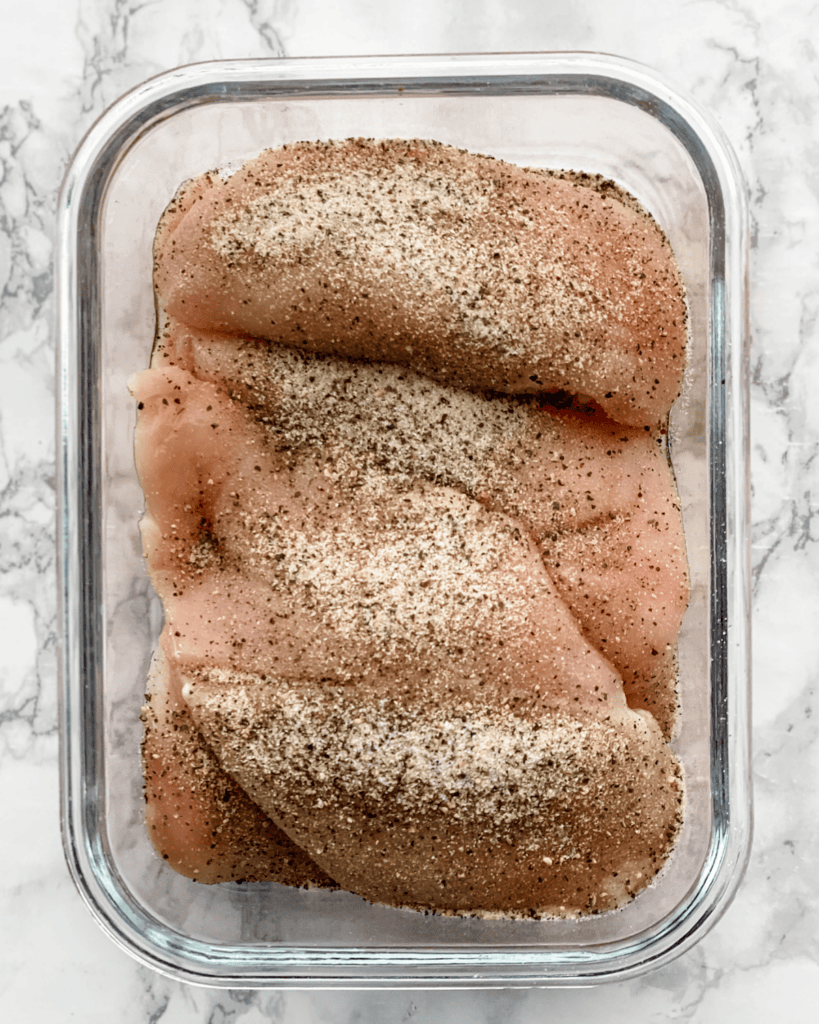 chicken in a glass container with seasoning.