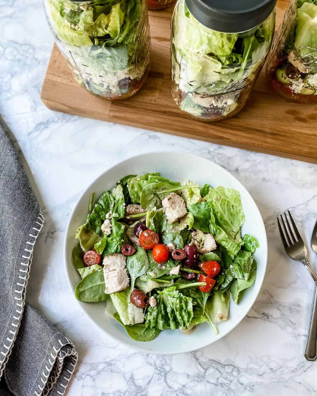 overhead of greek salad in a bowl and in jars
