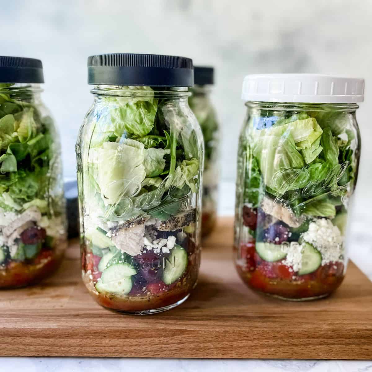mason jar salad in a row on a cutting board.