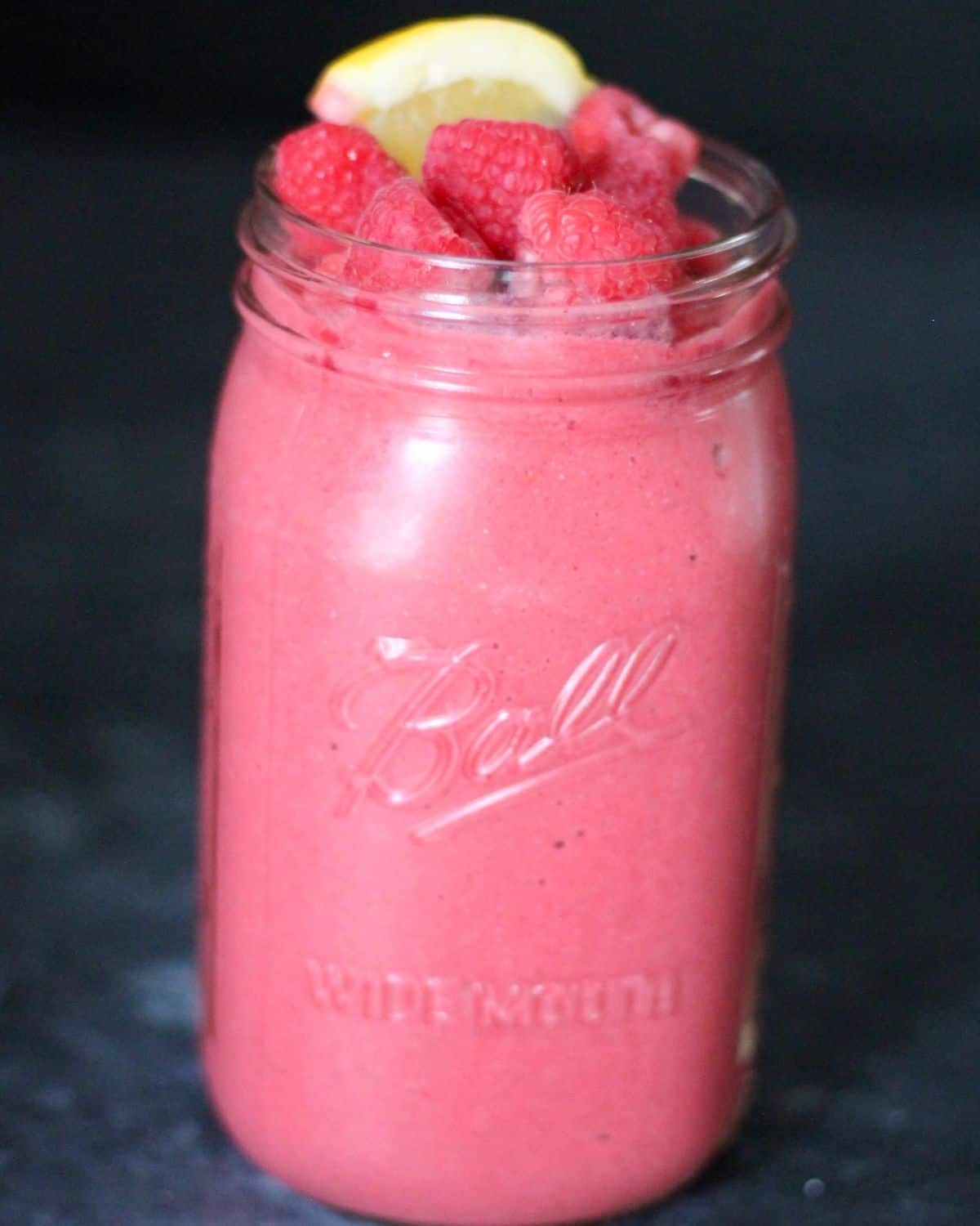 raspberry peach smoothie in a mason jar.