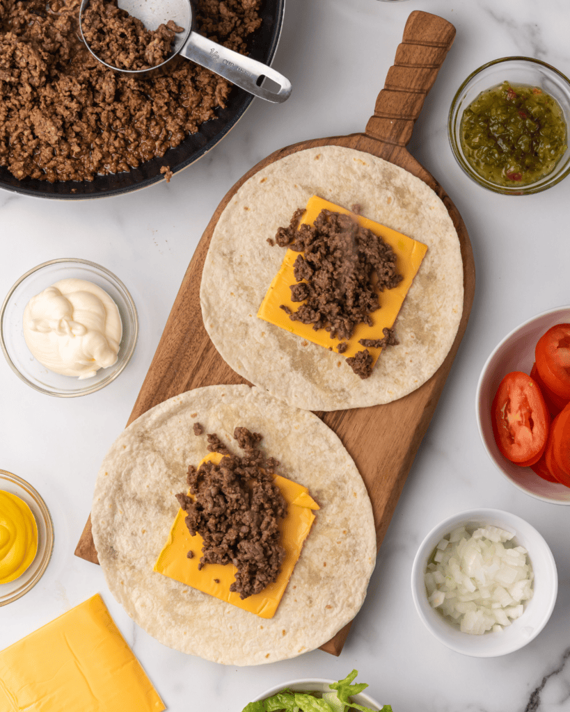 ground beef on cheese on top of the tortilla