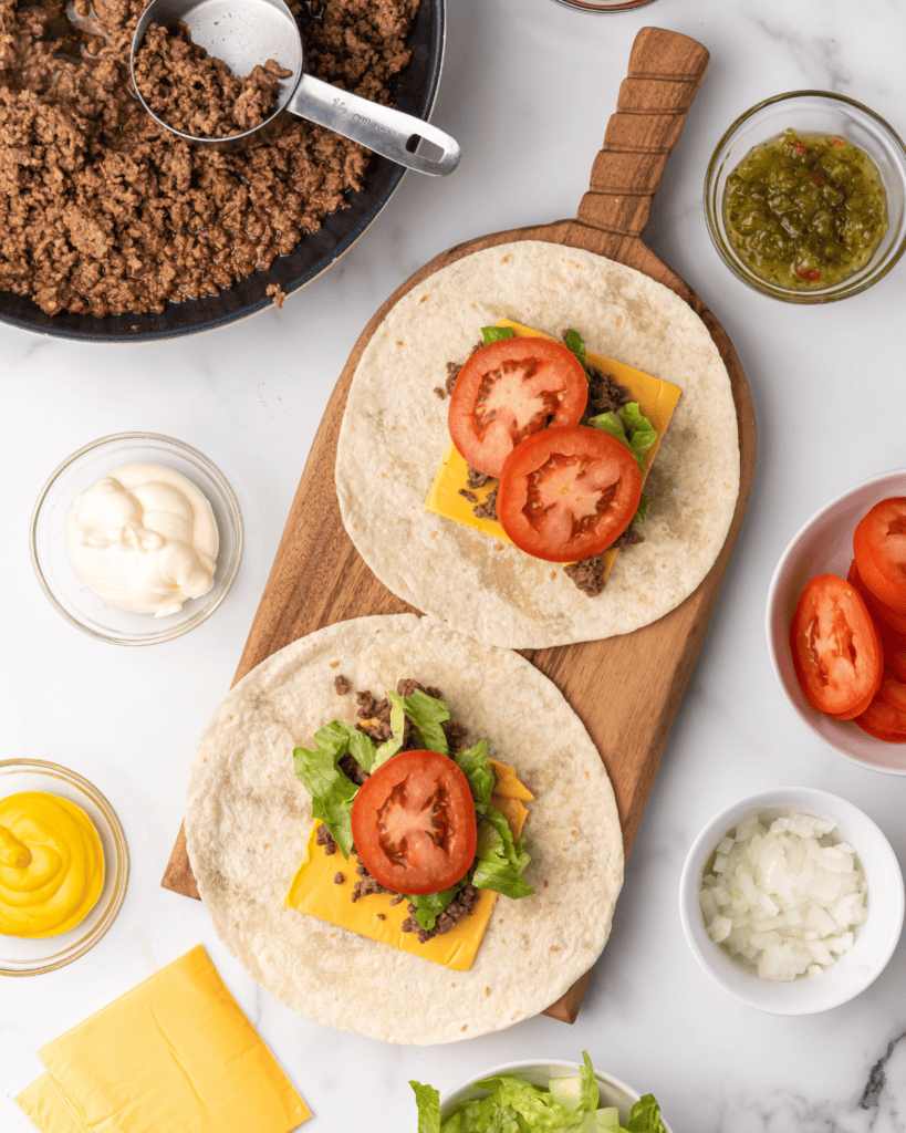 tomato and lettuce on the ground beef and cheese in tortilla.