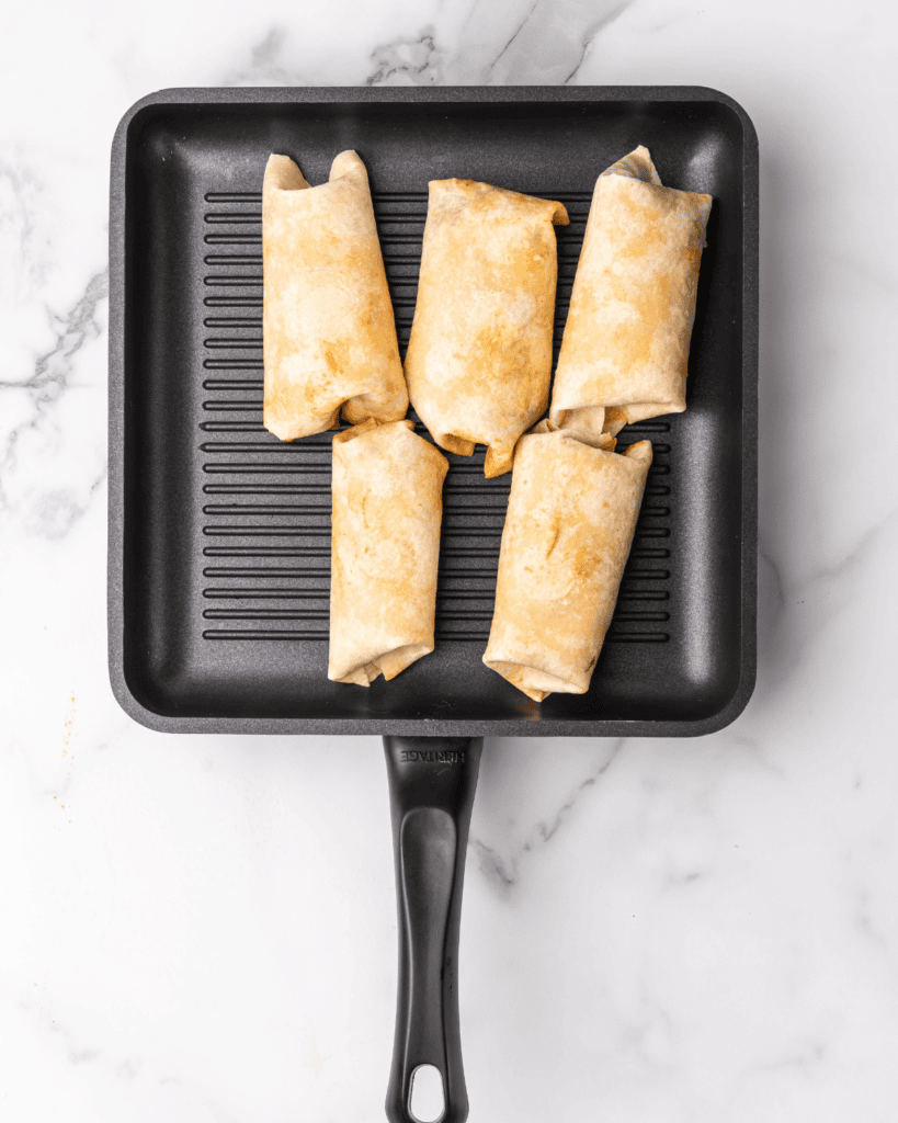 burgers wraps uncooked on a grill pan.