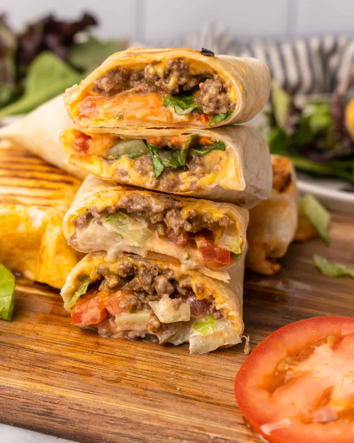 ground beef burger wraps stacked on cutting board.