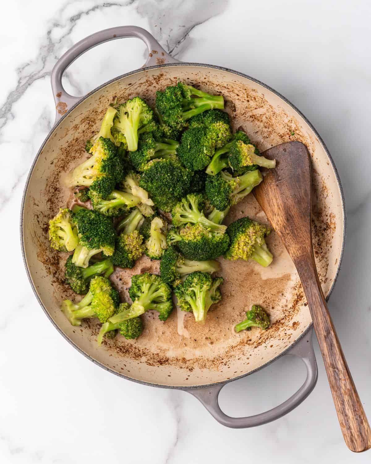 broccoli in a pot with a wooden spoon.