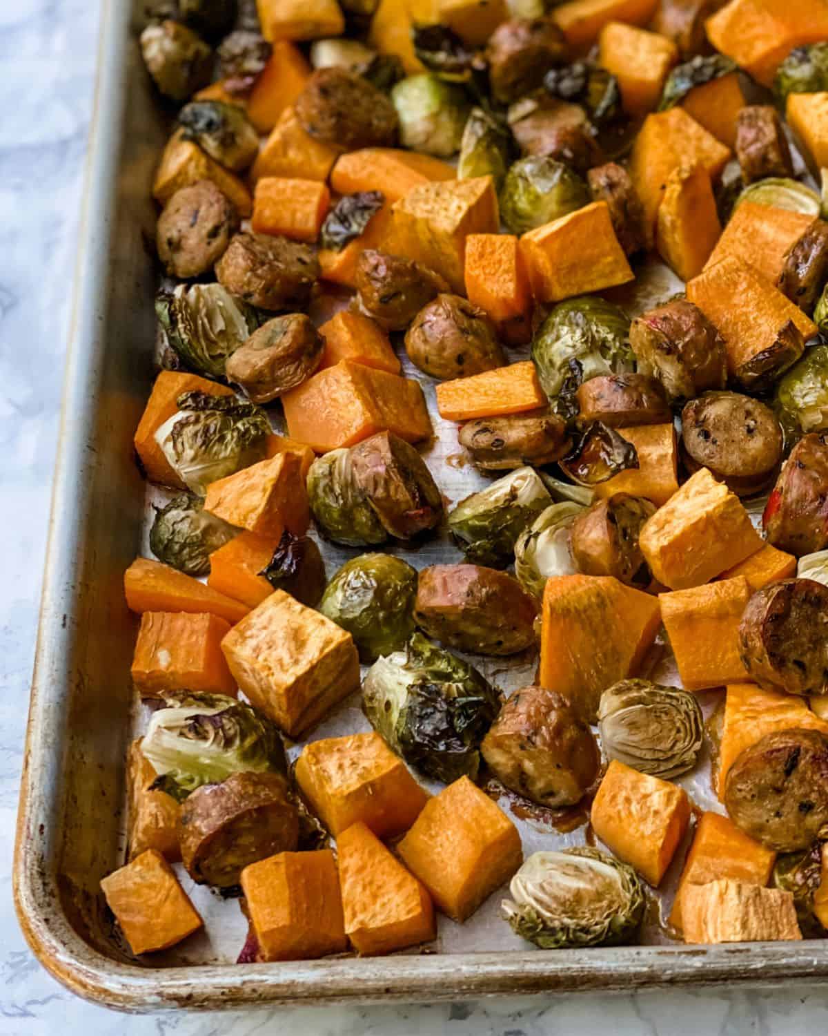 sausage, sweet potatoes, and Brussels sprout cooked on a baking sheet.