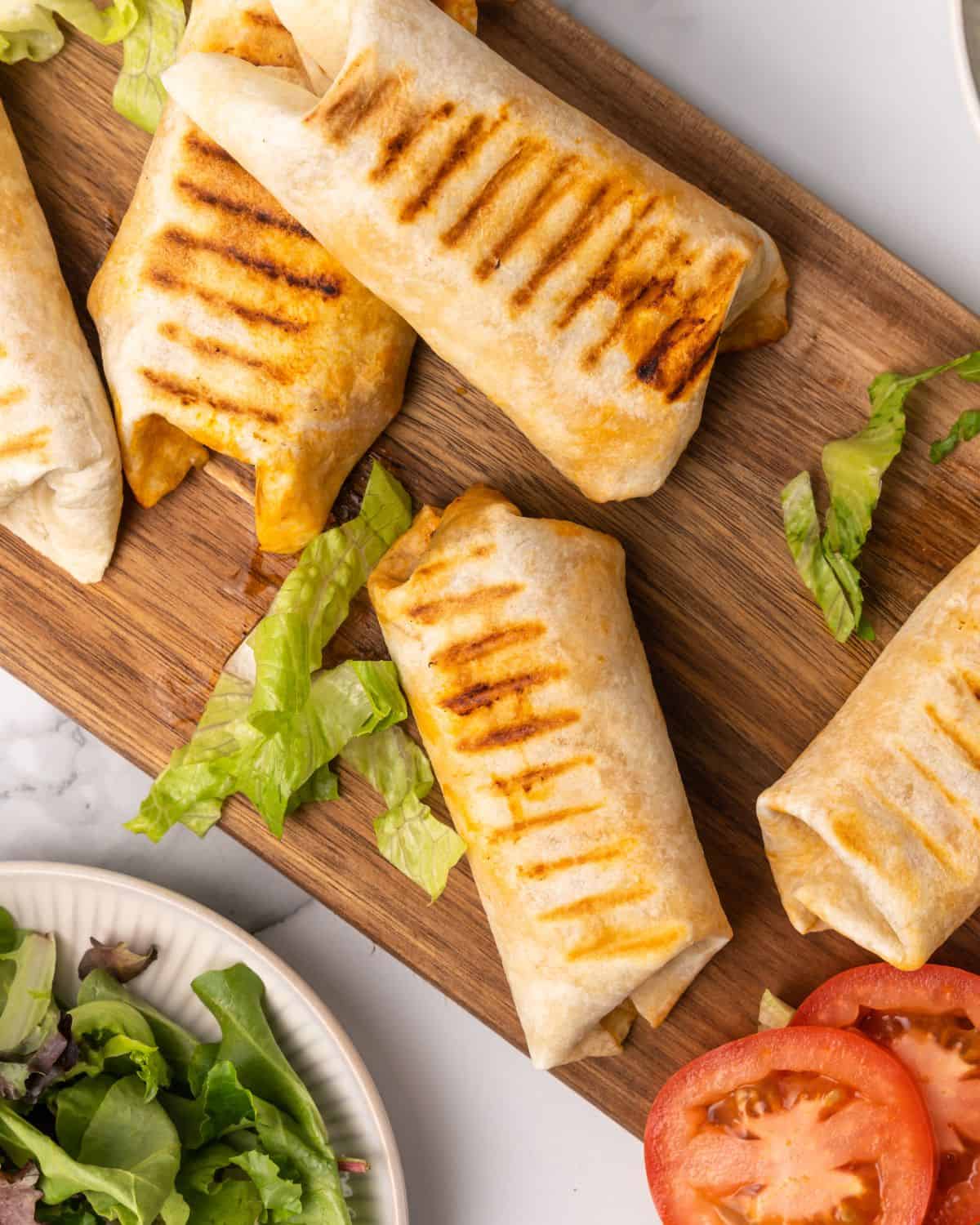 cooked burger wraps on a cutting board.