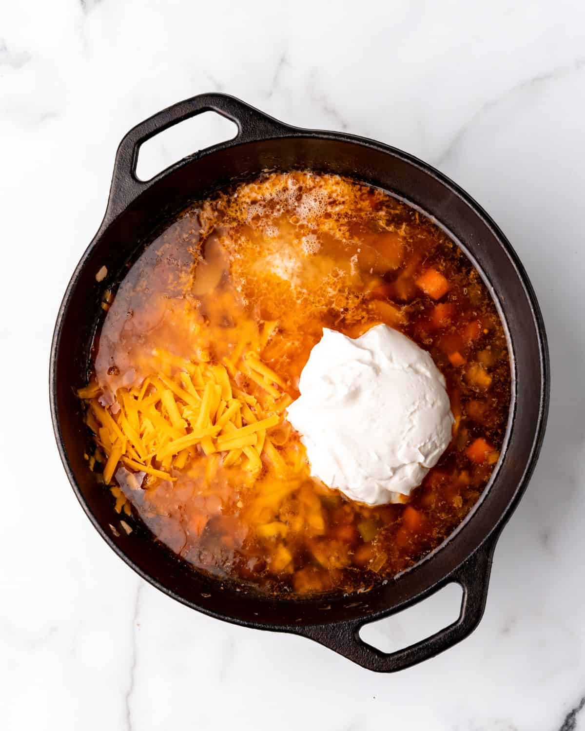 cheese and sour cream added to the soup pot.