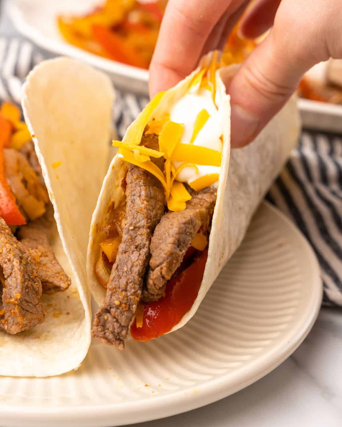 two beef fajitas on a plate.