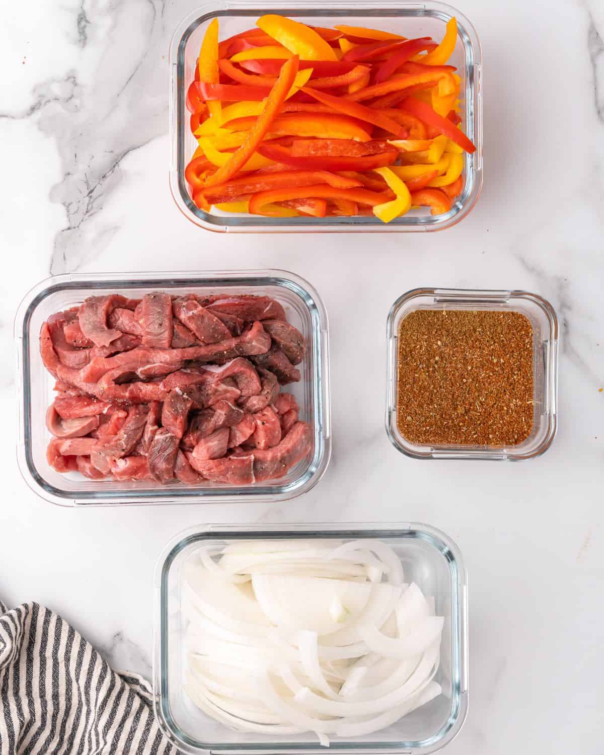 overhead picture of steak fajita ingredients in glass containers.