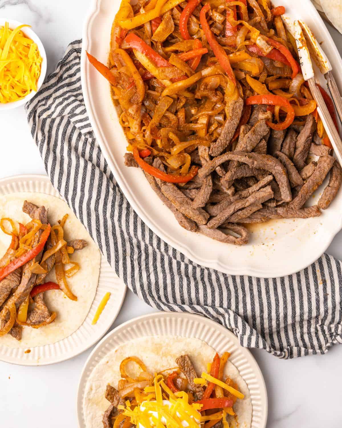 overhead picture of steak fajitas and peppers and onions on a platter.