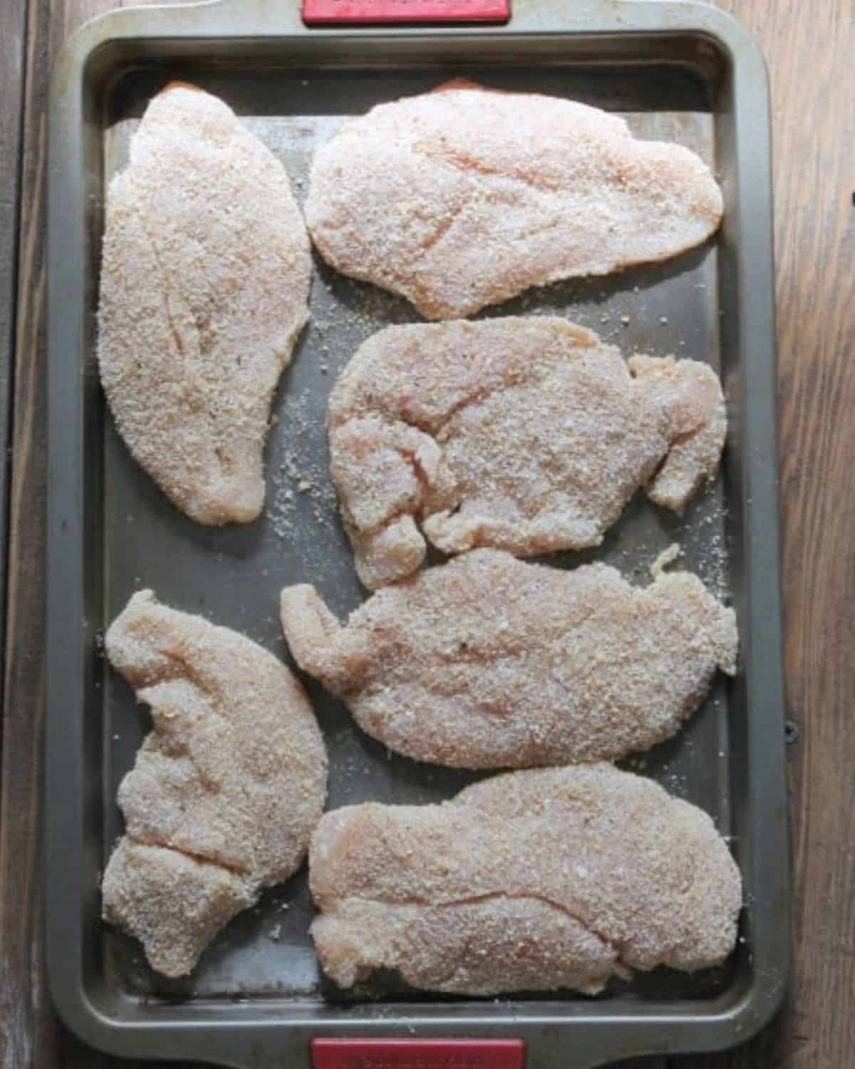 chicken breaded and then placed on a baking sheet.