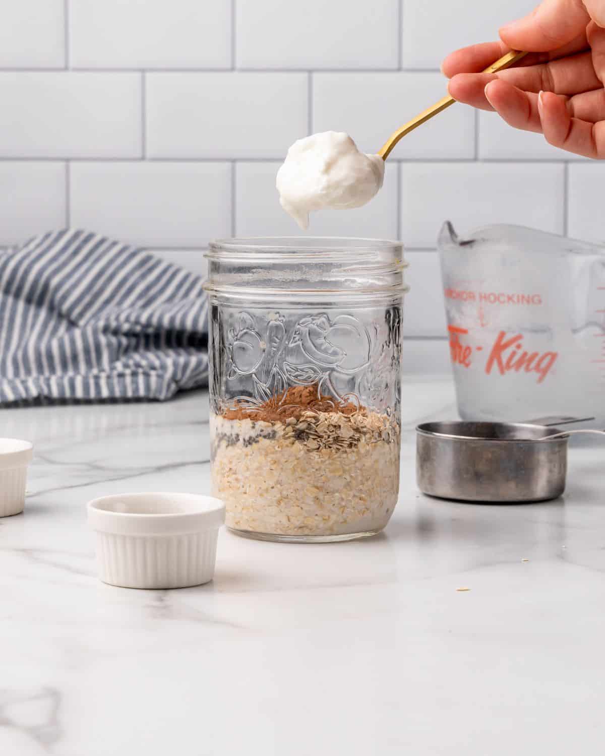 adding greek yogurt into a mason jar.