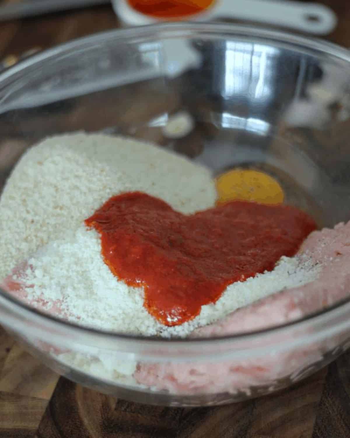 ingredients in a bowl for chicken parm meatballs.