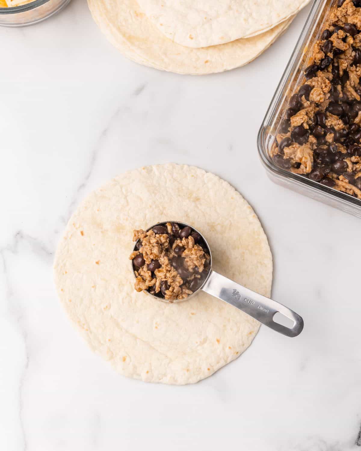 turkey mixture in a measuring cup on a tortilla.