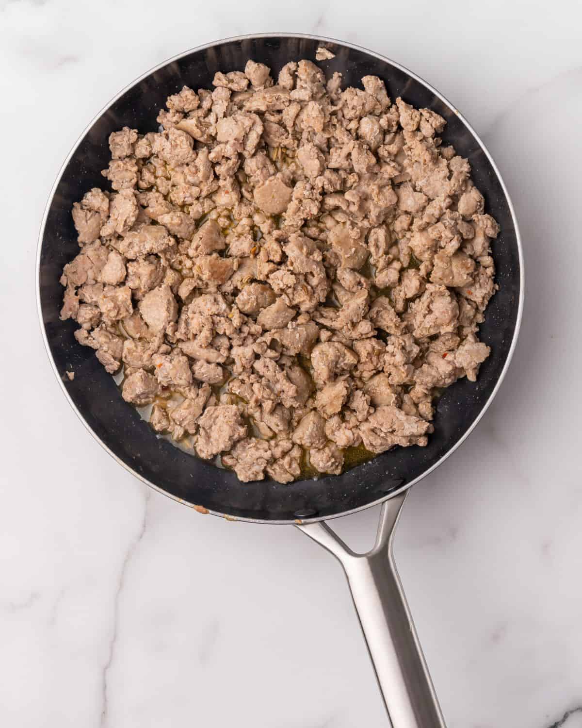 chicken sausage cooked and crumbled in a pan.