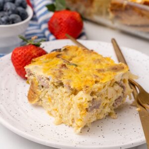 a piece of make-ahead sausage hash brown casserole on a plate with strawberries.