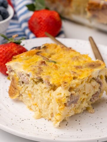 a piece of make-ahead sausage hash brown casserole on a plate with strawberries.