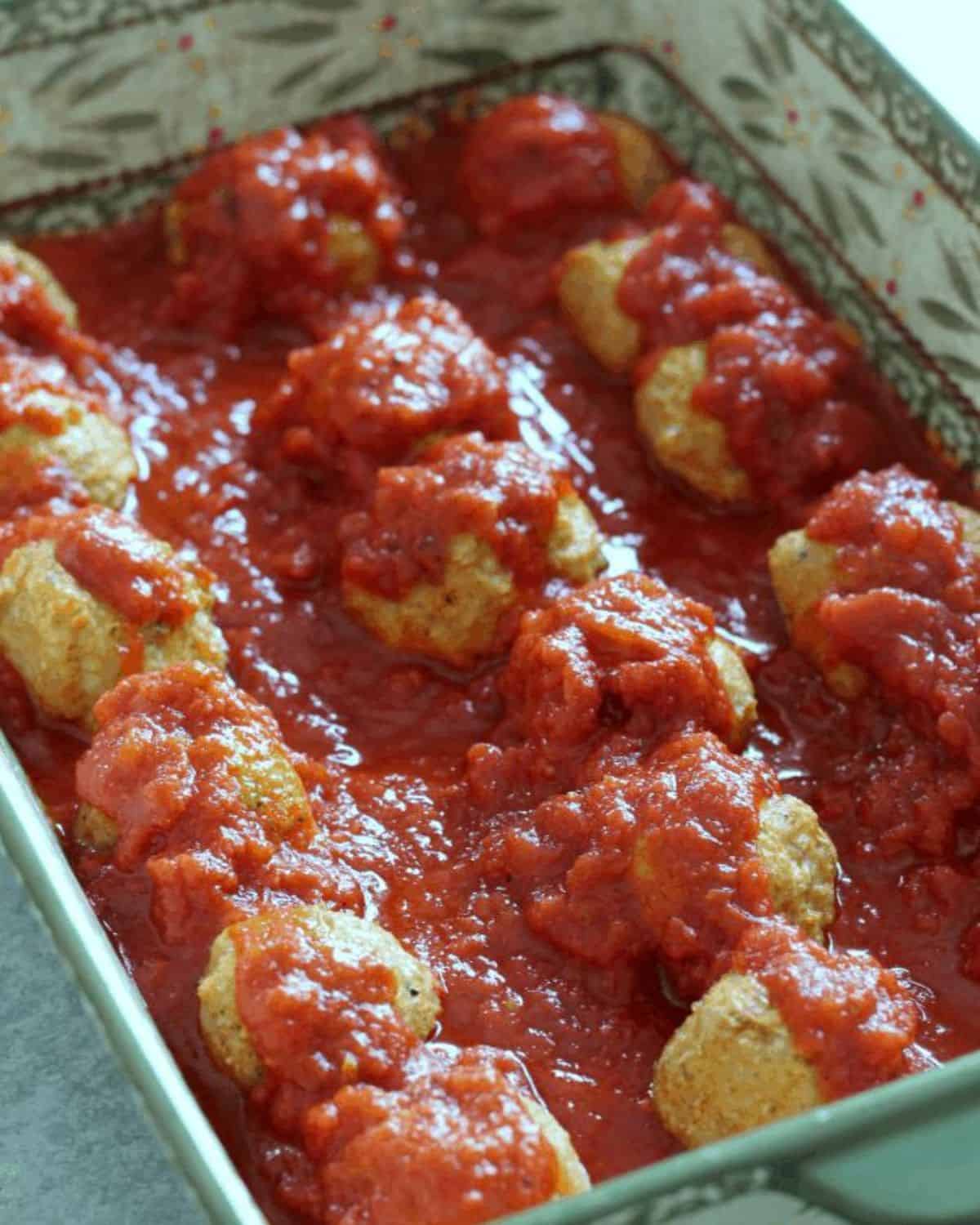 baked chicken parm meatballs in a casserole pan.